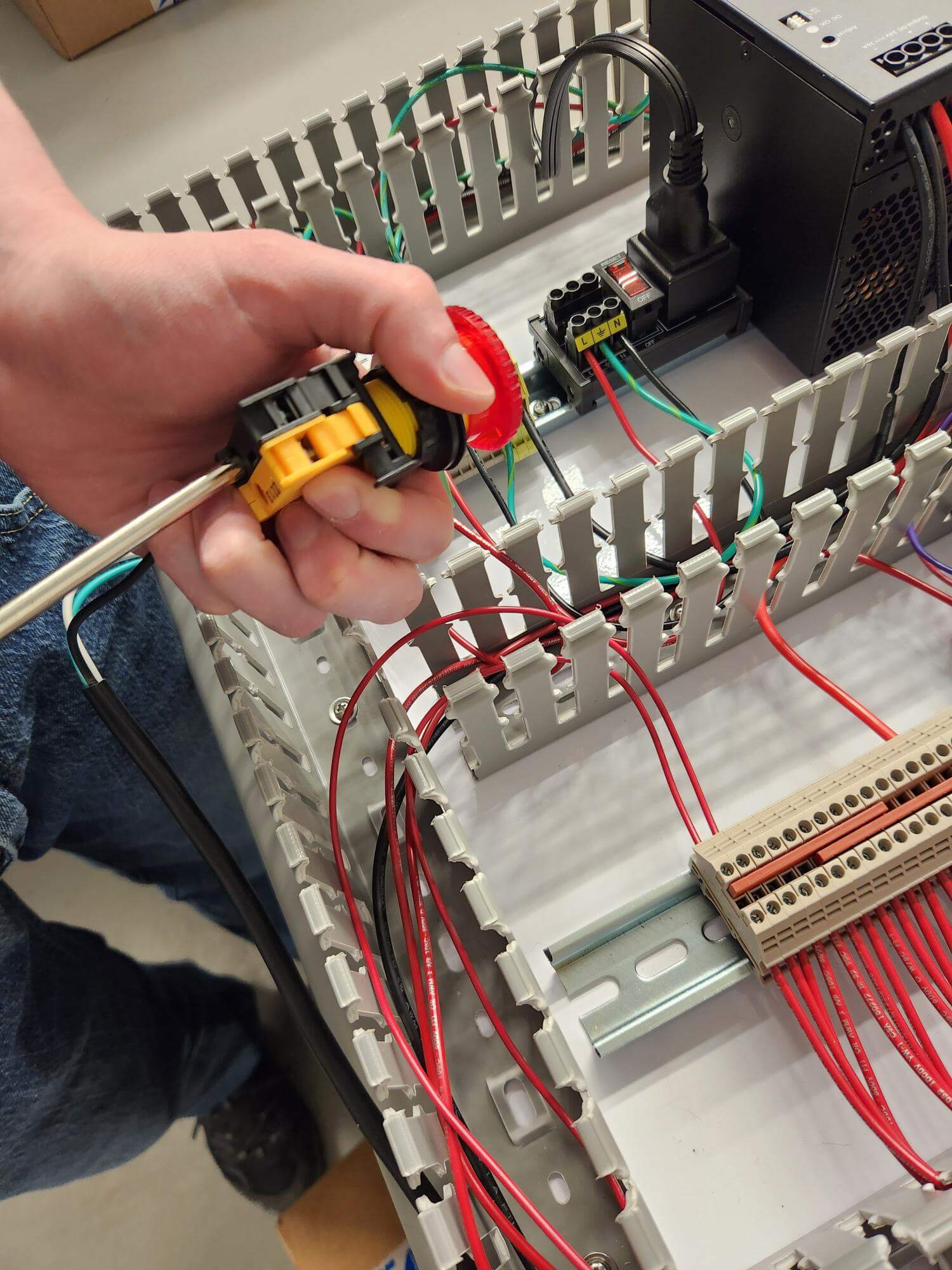 VoxSomnia staff wiring up an E-Stop for a new test bench control panel.